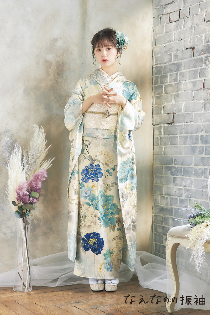 なえなの振袖。淡いミントブルーの地色に鮮やかな青い牡丹が映える、清涼感あふれるくすみカラー振袖。アンティークな背景に馴染む、最旬の二十歳スタイル。