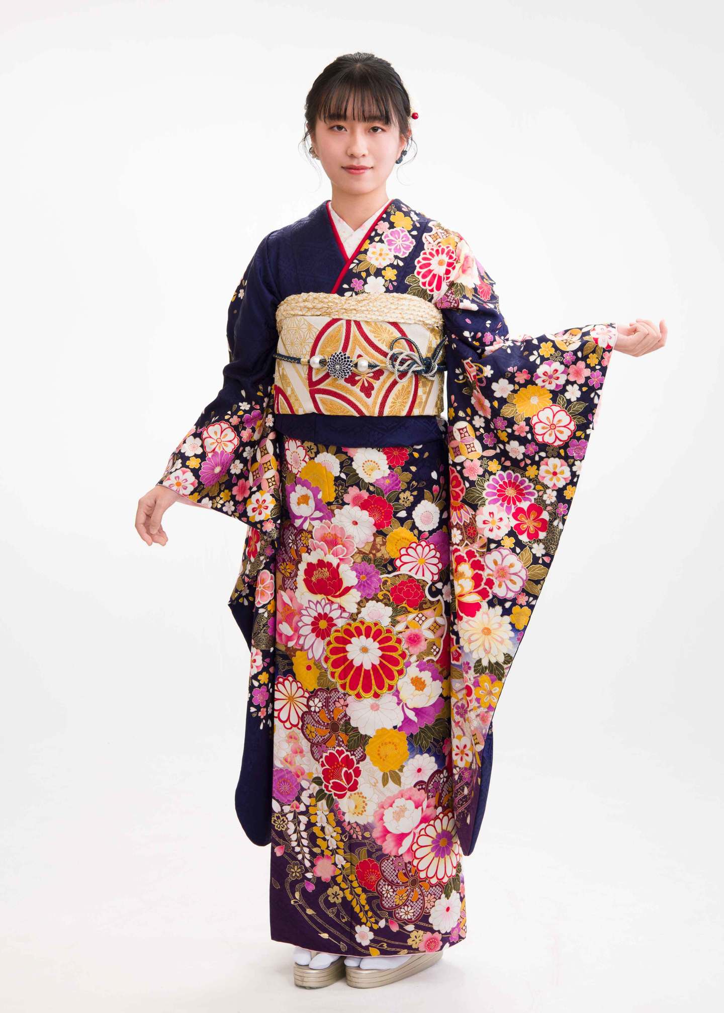 三原市・冨士写真館での振袖スタジオ撮影。紺地に色とりどりの花々が描かれた華やかな振袖と、白地に金の帯を合わせた気品あるコーディネート例。