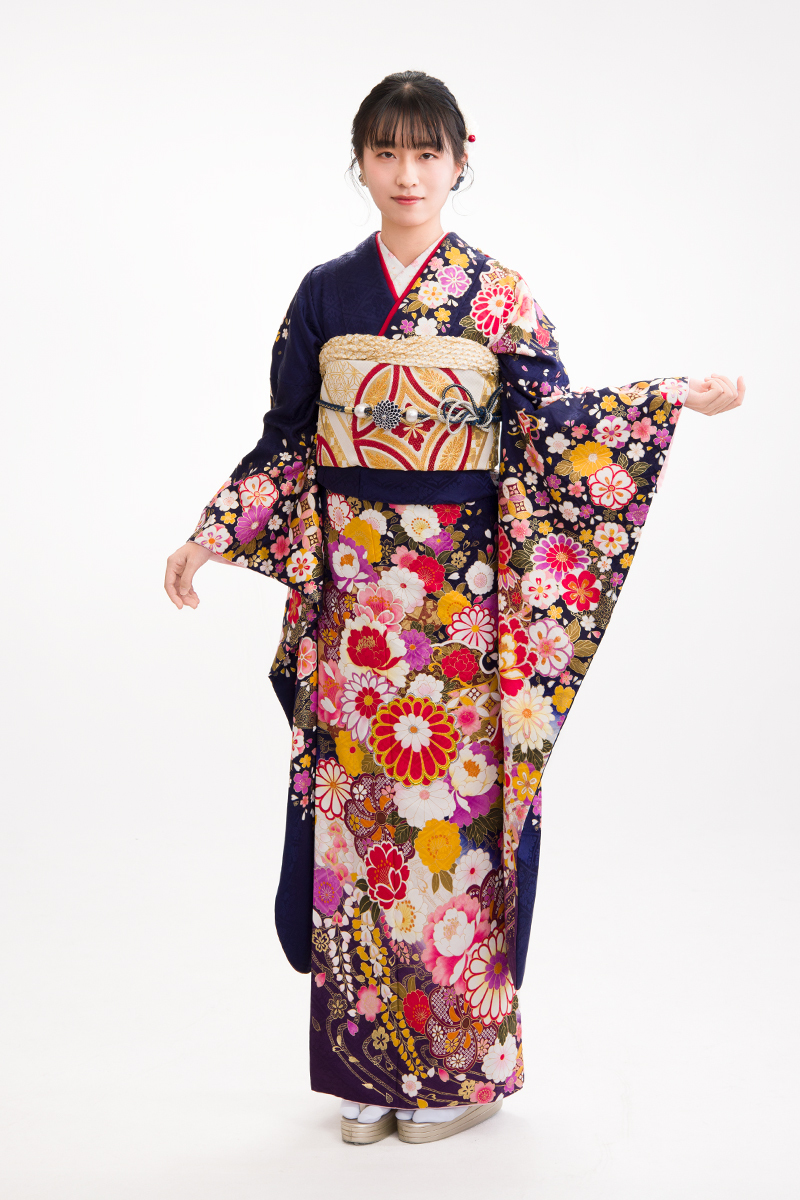 深みのある濃紺に色鮮やかな古典花が咲き誇る、知的な美しさが際立つ振袖。清楚さと華やかさを兼ね備えた、二十歳の門出を彩る凛とした装い。