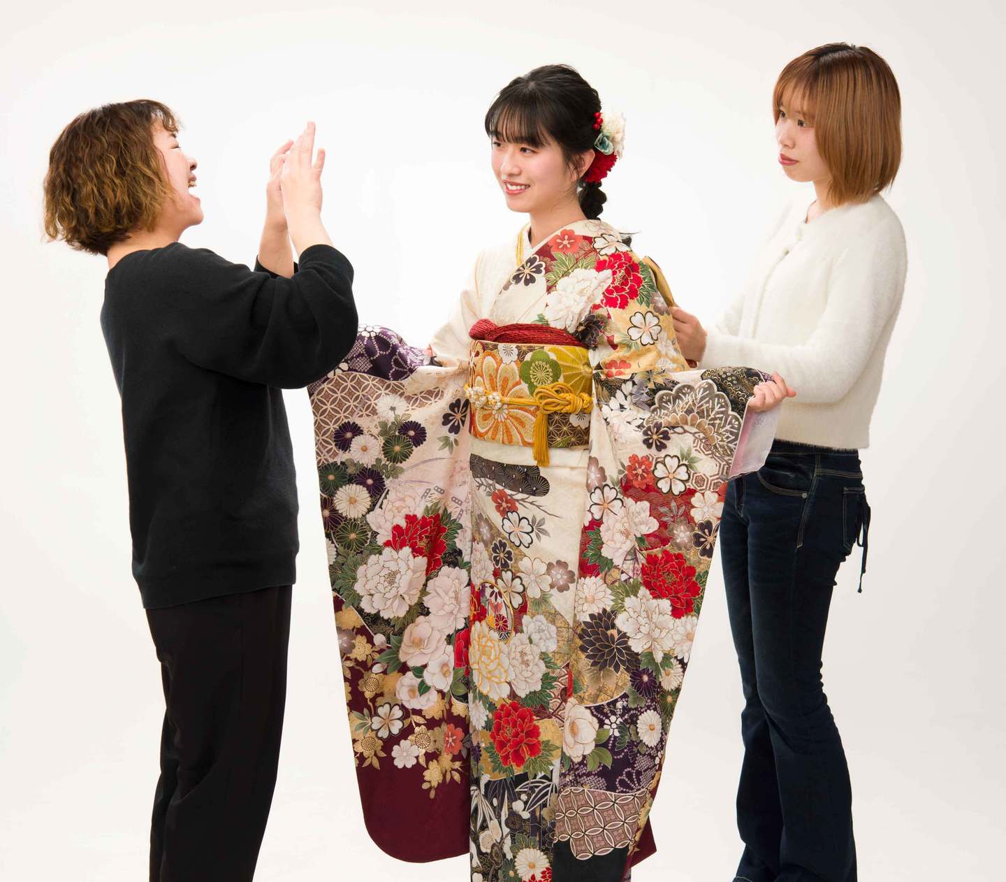 三原市・冨士写真館での振袖試着風景。経験豊富なスタッフがお嬢様に似合う着こなしを丁寧にアドバイス。白地に赤い花柄が映える振袖を実際に羽織って、成人式当日の姿を確認できます。